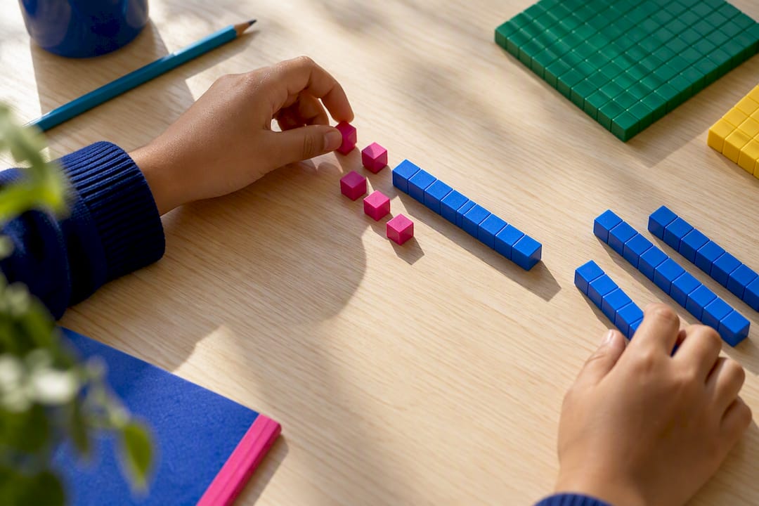 Hands arranging base ten block pieces